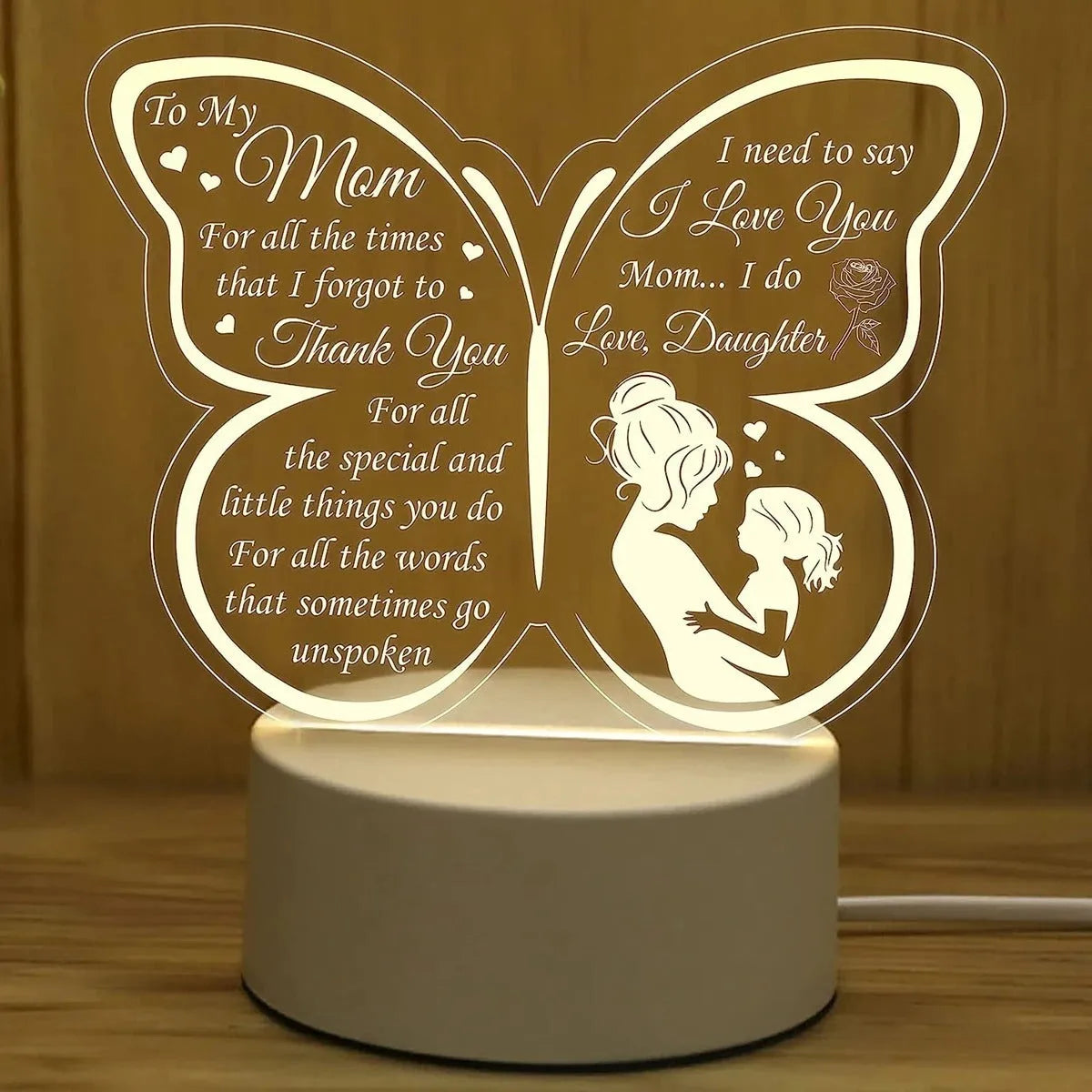 White heart-shaped acrylic table lamp with glowing warm light on a wooden surface.