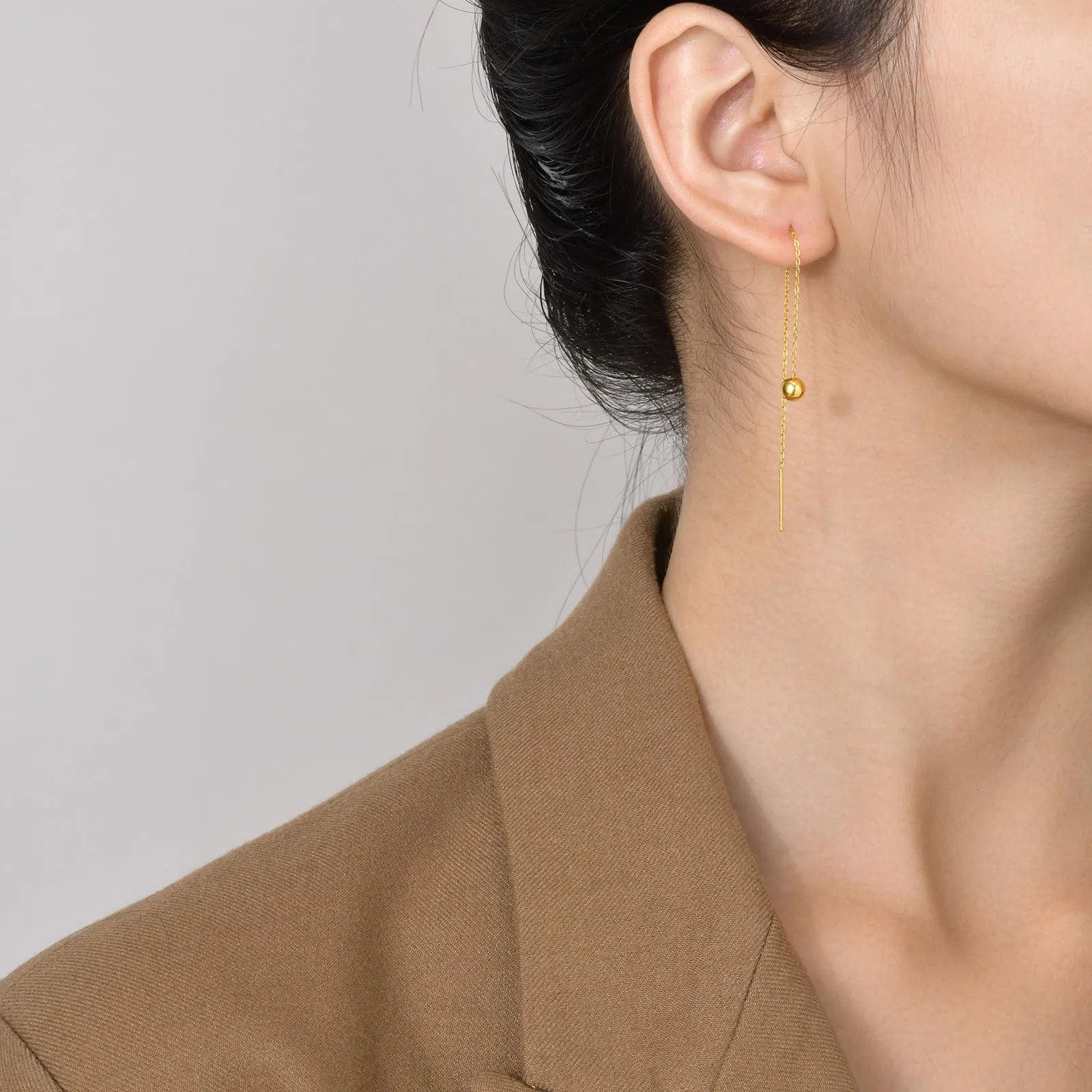 Gold-toned alloy drop earrings with round bead design on white background