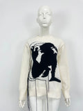 Grey women's loose alpaca wool sweater with abstract pattern and tassel detail on sleeve.