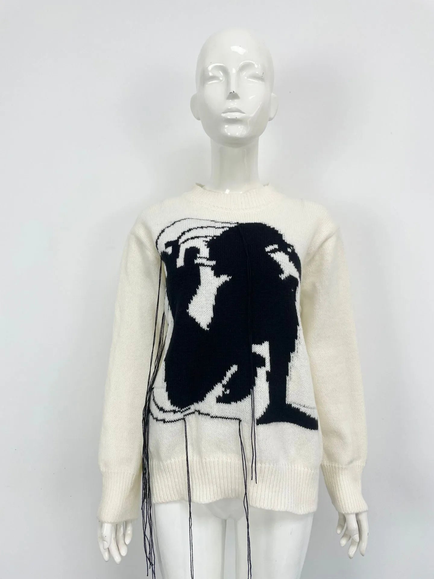 Grey women's loose alpaca wool sweater with abstract pattern and tassel detail on sleeve.