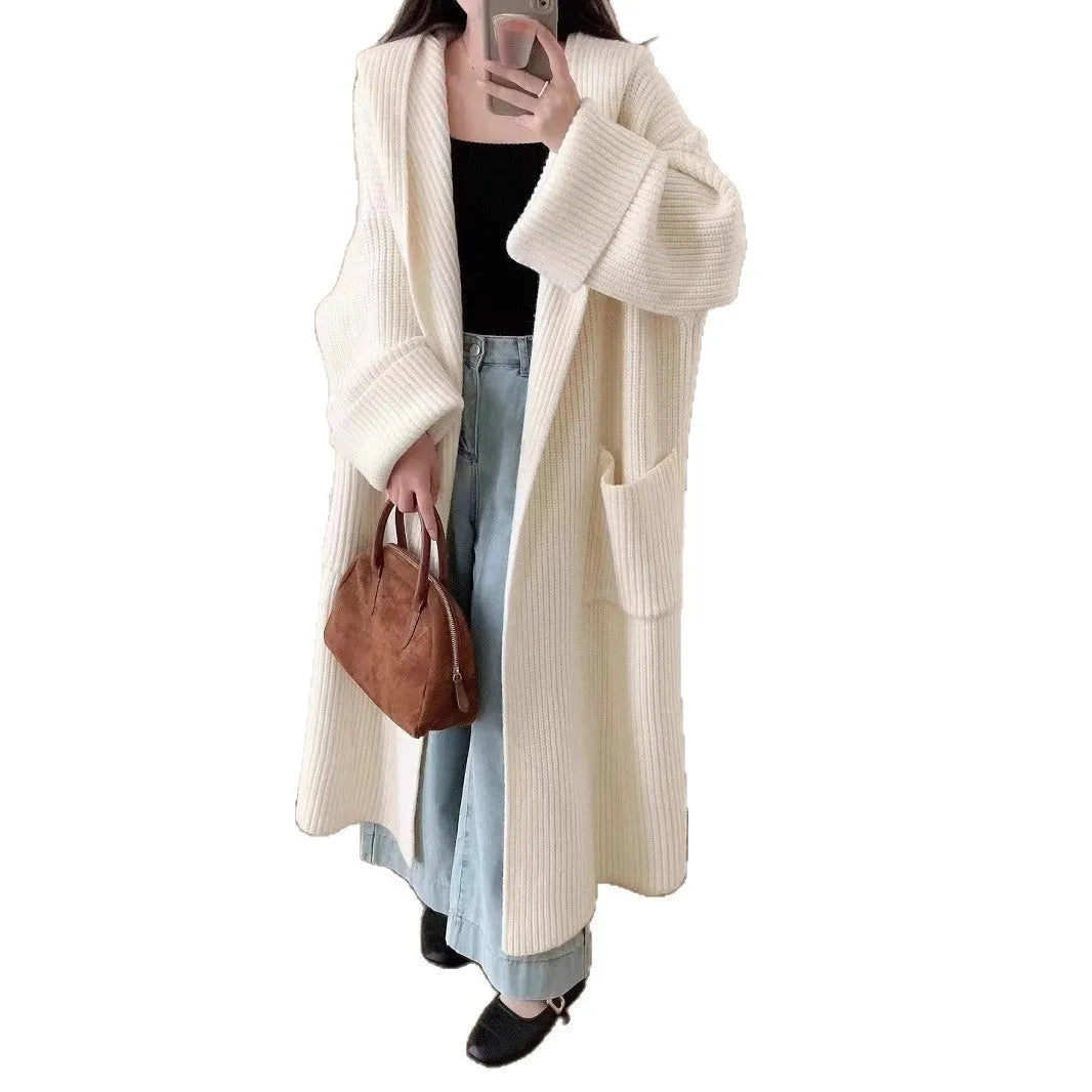 A woman wearing a long, loose, hooded cardigan coat in a neutral colour, showing its oversized fit and length.