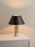 Modern black table lamp with a textured marble base on a wooden desk.