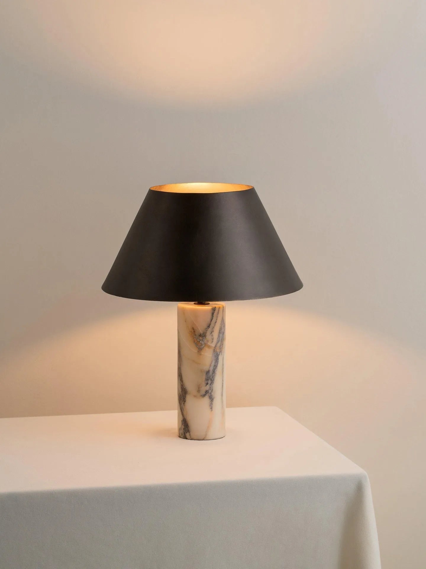 Modern black table lamp with a textured marble base on a wooden desk.