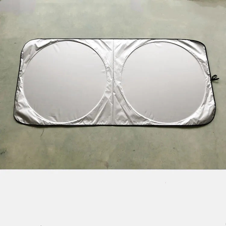 Large silver reflective car sunshade folded next to its cloth storage bag