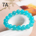 Selection of natural green Amazonite scattered beads in different sizes on a white background.