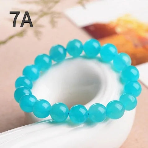 Selection of natural green Amazonite scattered beads in different sizes on a white background.