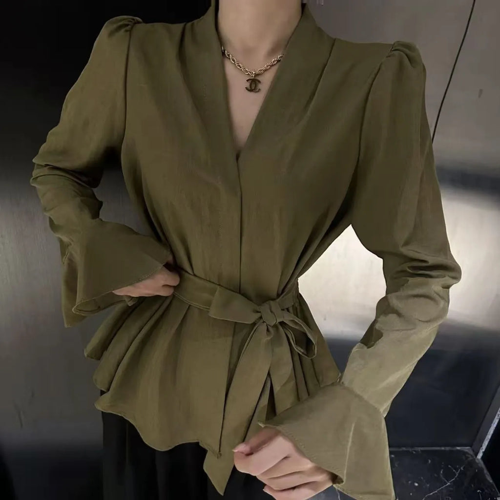 Woman wearing a black tied shirt with a French-style collar and long bell sleeves.