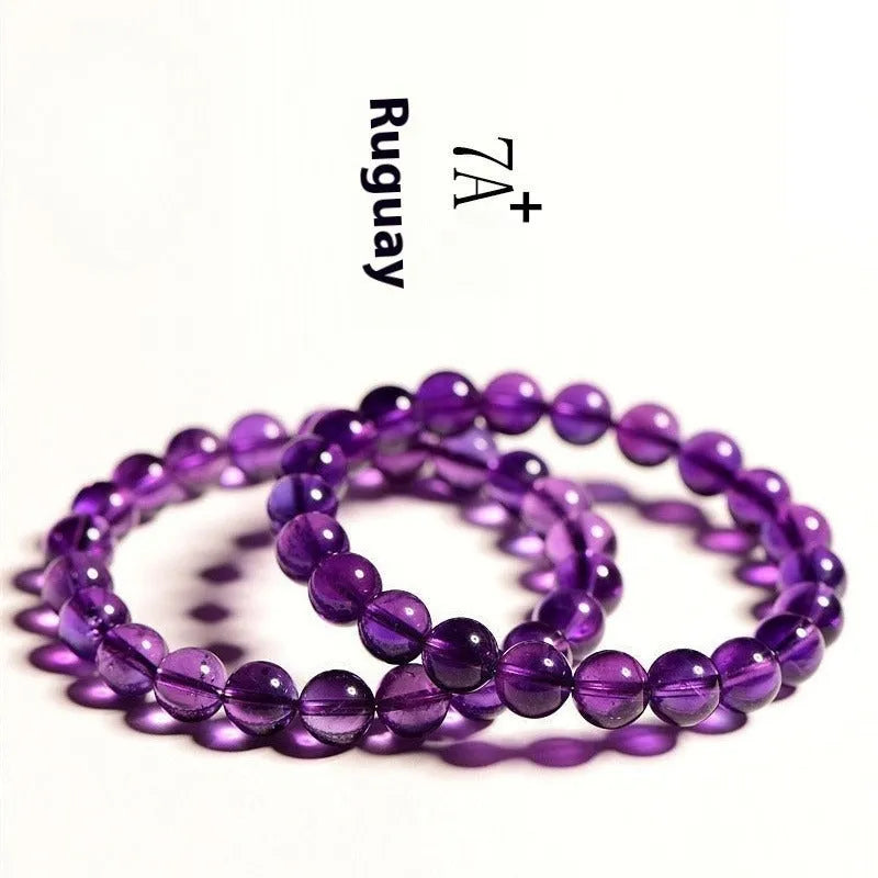 Close-up of a natural purple amethyst bead bracelet with elastic band on a wrist.