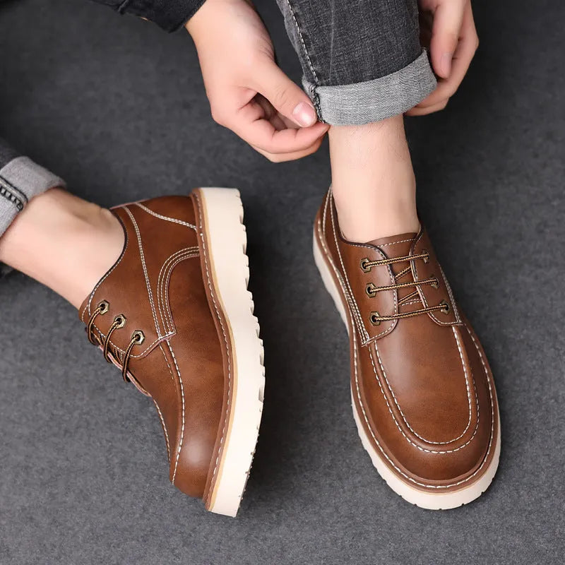 Men's black low-top Martin boots with a round toe and rubber sole on a plain background.