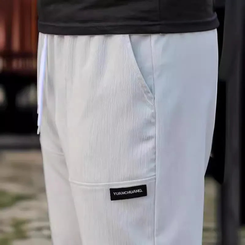 Men's light grey polyester trousers for spring and autumn casual wear, laid flat.