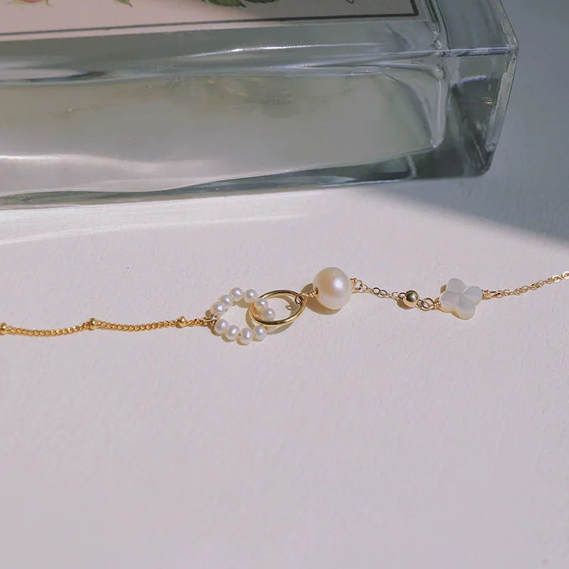 Women's natural freshwater pearl bracelet with gold-plated clasp and floral charm accents on a white background.
