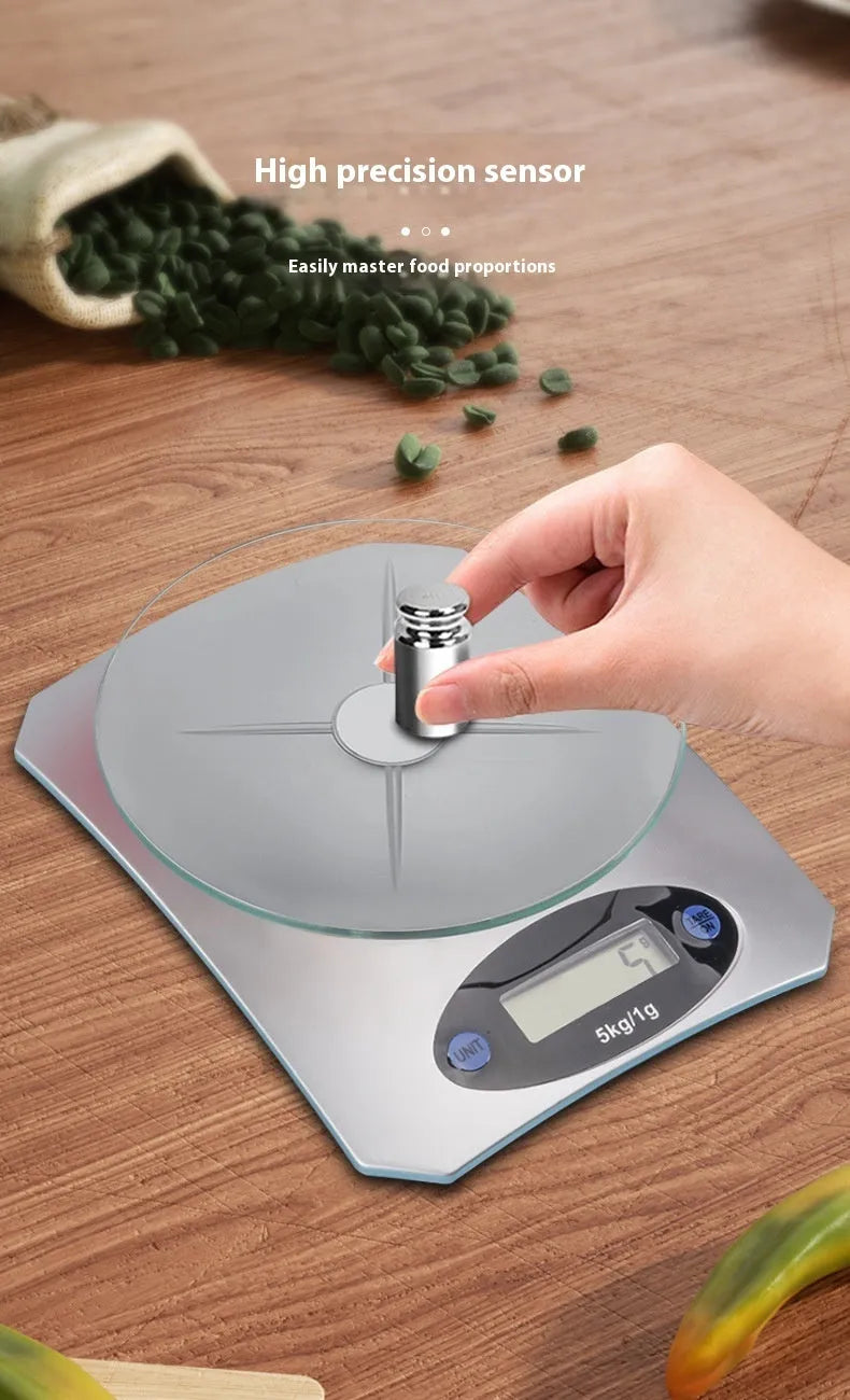 Simple mini kitchen electronic scale in silver white colour on a flat surface, showing weighing display.