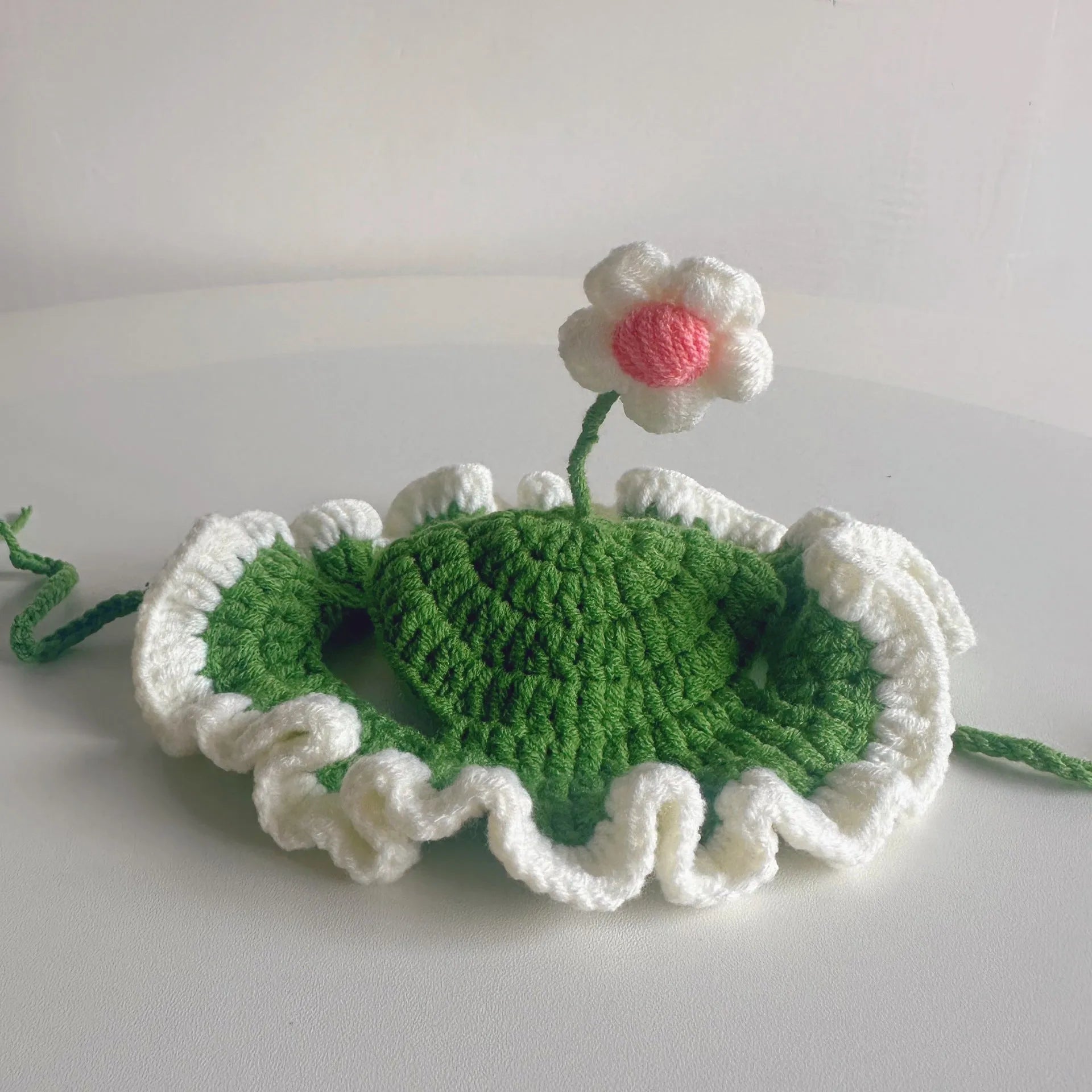 Green knitted cartoon cat hat on a pet mannequin head showing soft fabric and costume design.