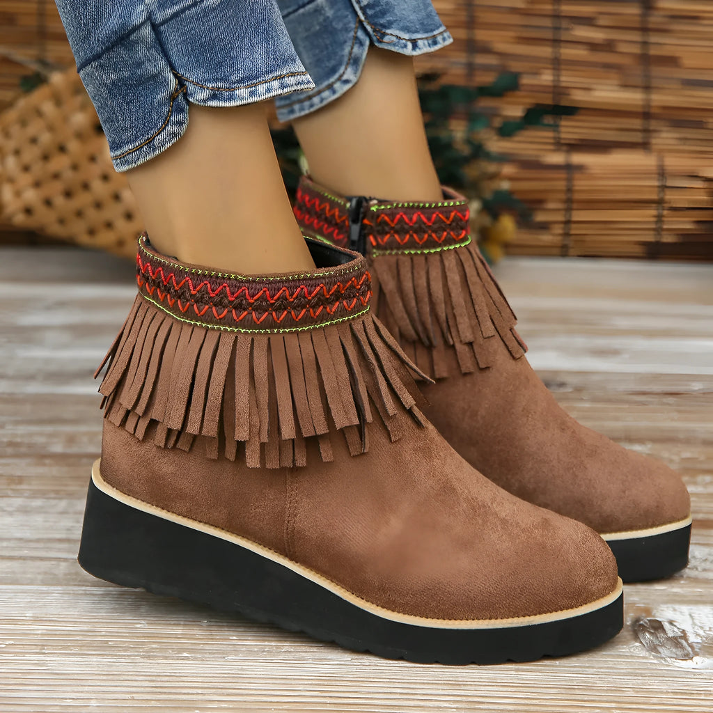 Women's black wedge bootie with suede upper, thick rubber sole, side zipper, and tassel detail.