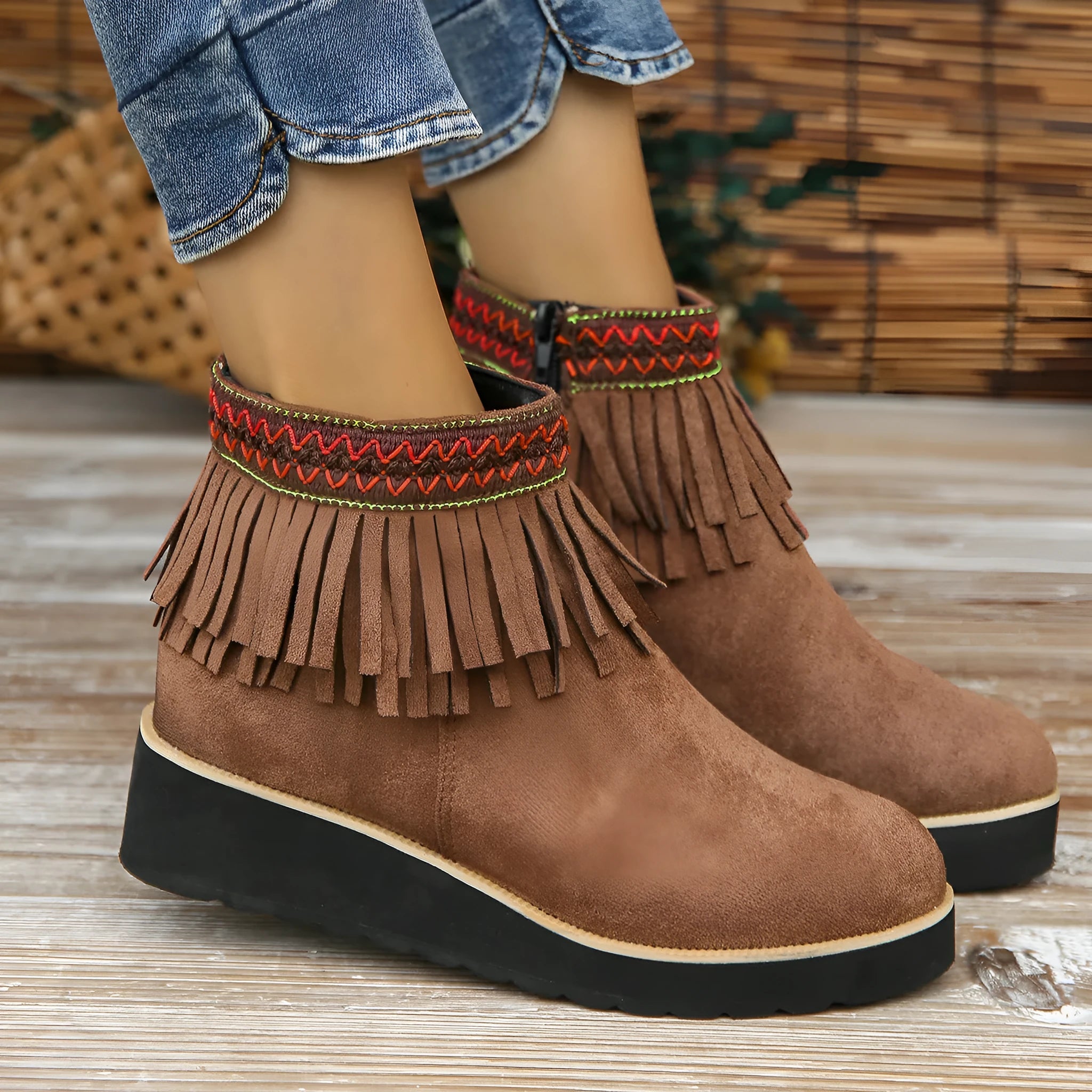 Women's black wedge bootie with suede upper, thick rubber sole, side zipper, and tassel detail.