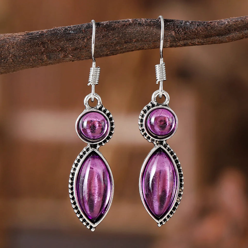 Close-up of geometric vintage pendant earrings in black and purple with a metallic shine.