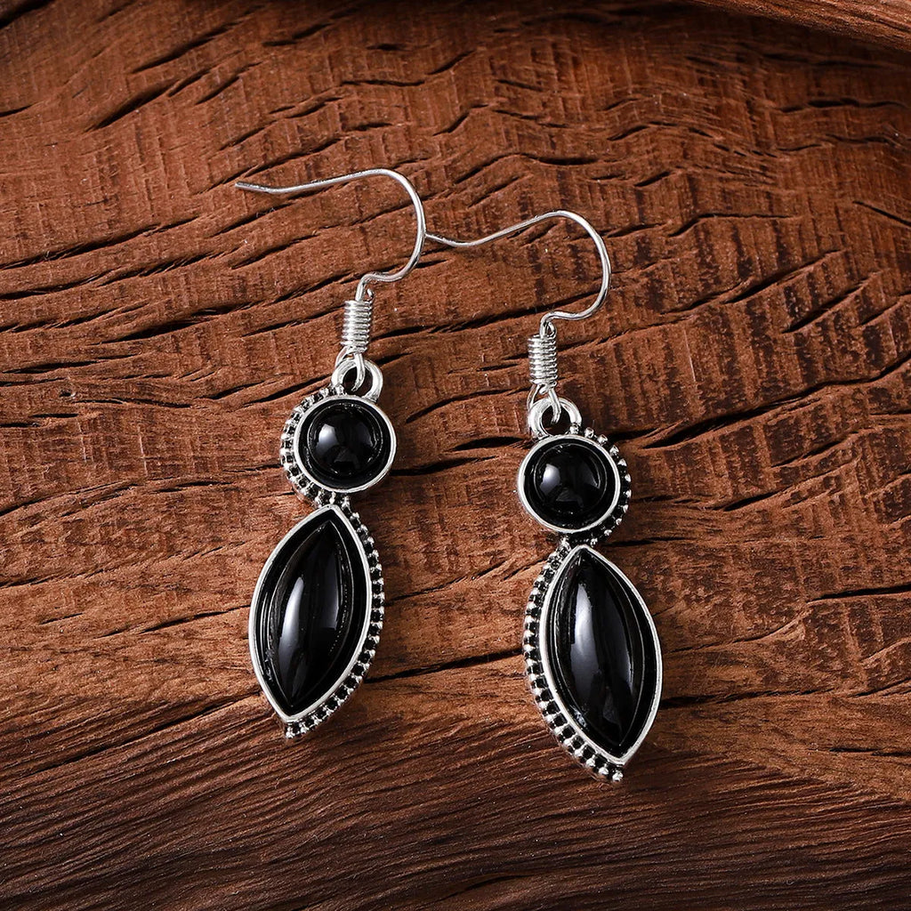 Close-up of geometric vintage pendant earrings in black and purple with a metallic shine.