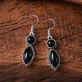 Close-up of geometric vintage pendant earrings in black and purple with a metallic shine.
