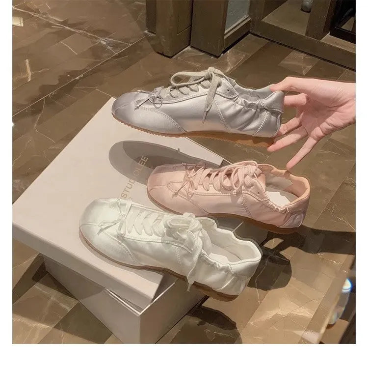 Women's satin ballet flats in champagne pink with round toe and front lace-up closure.
