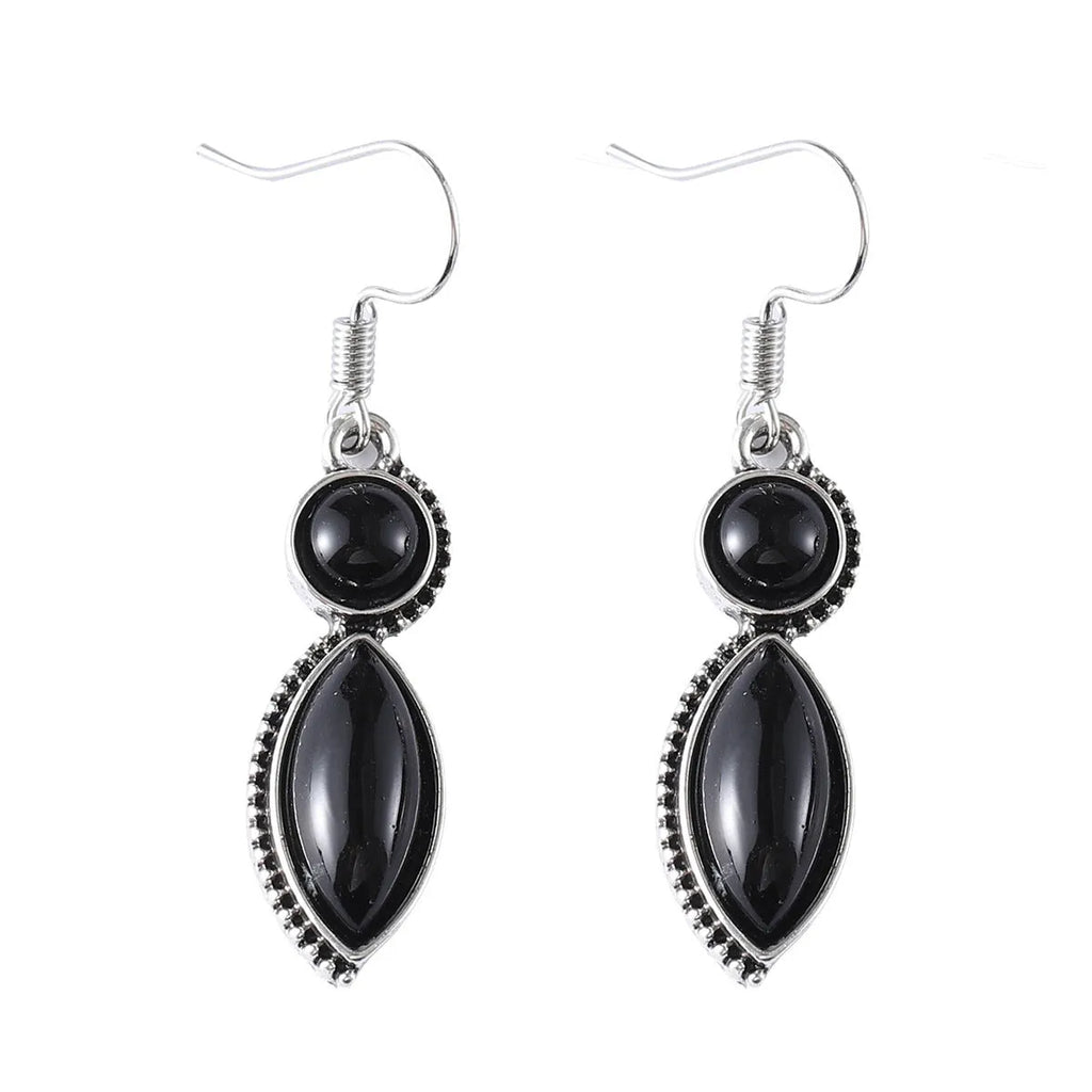 Close-up of geometric vintage pendant earrings in black and purple with a metallic shine.