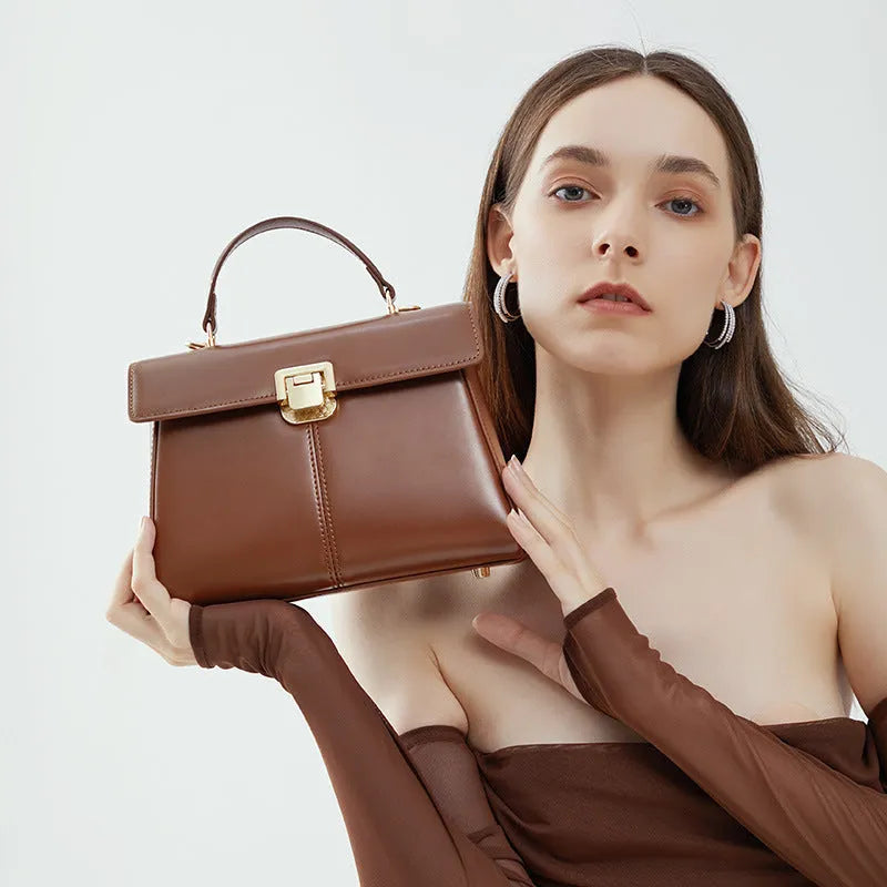 Black genuine leather women's shoulder bag with a clasp closure and long adjustable strap.