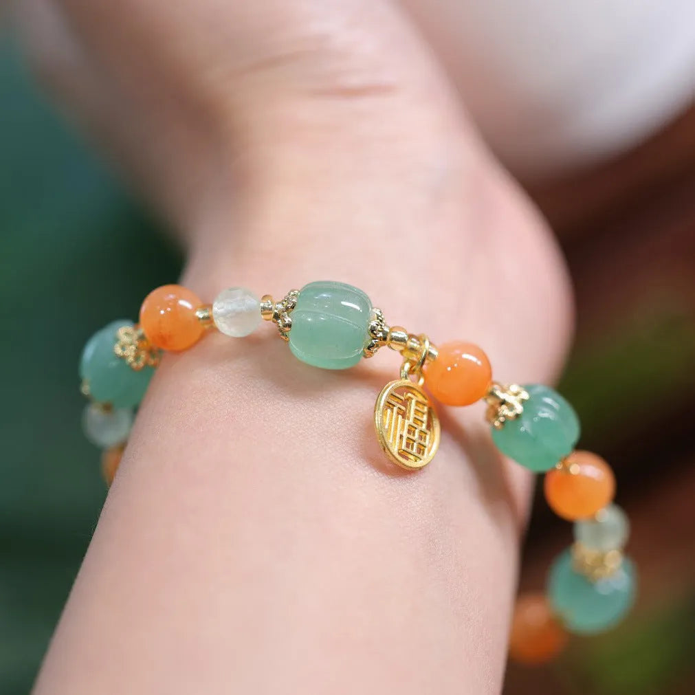 Close-up of a jade and prehnite Chinese-style pumpkin bead bracelet on a wrist.