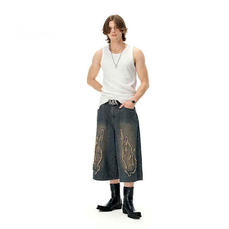 Men's black denim shorts with flame embroidery and a cropped patch on the leg.