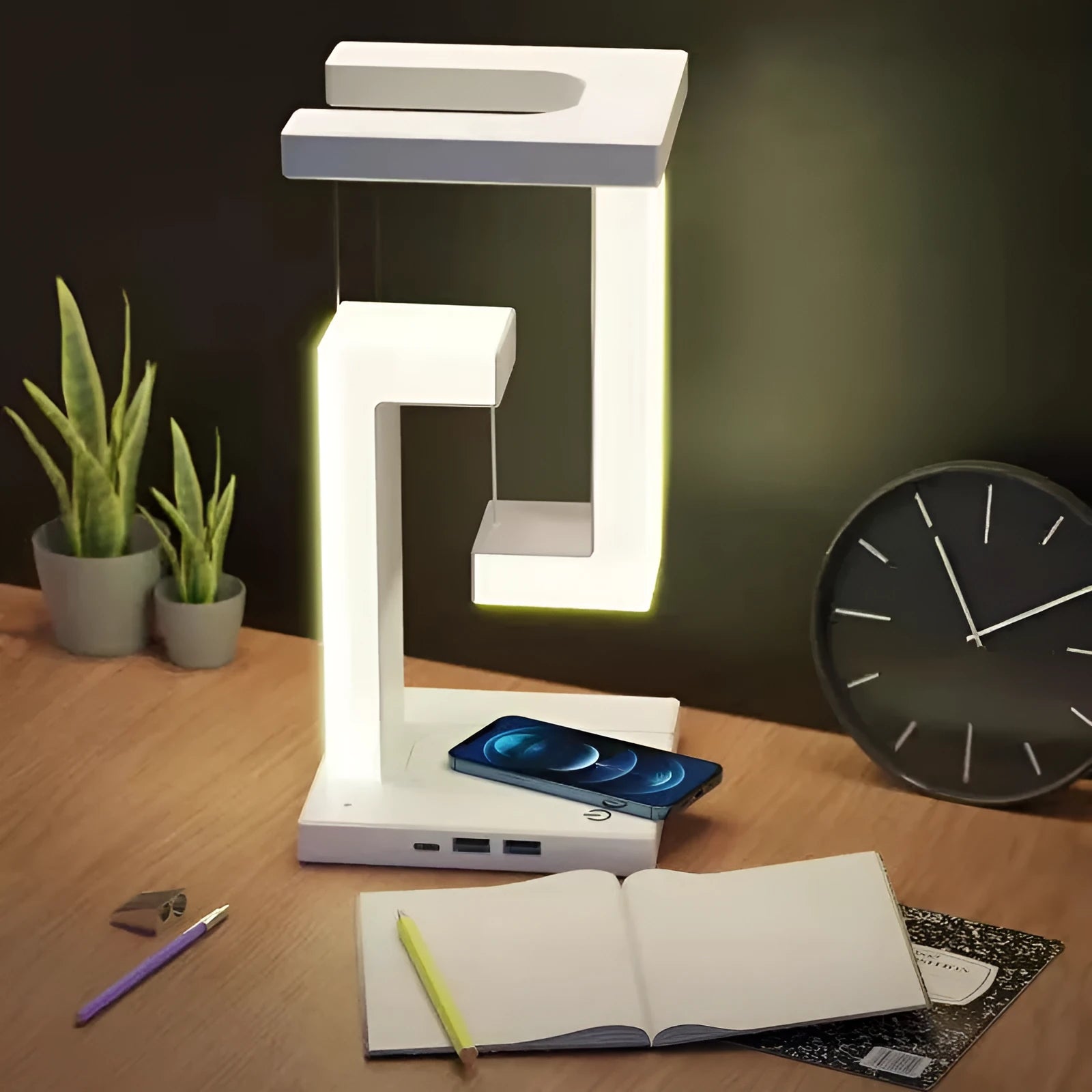 White magnetic suspension table lamp with wireless charging base, floating shade, and foldable bracket on a desk