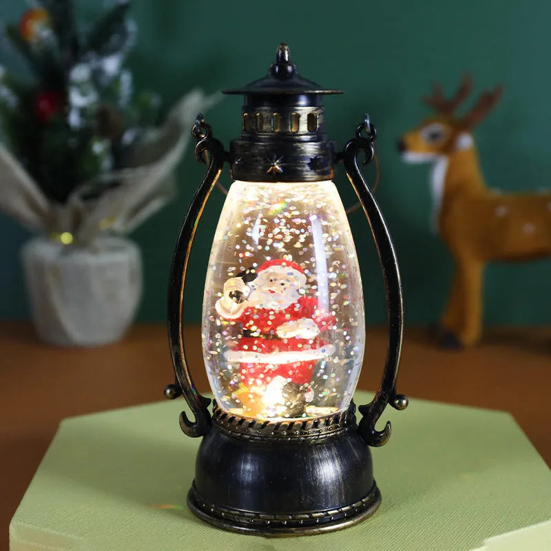 Plastic crystal ball LED oil lamp Christmas decoration showing internal snowman scene on a desktop.