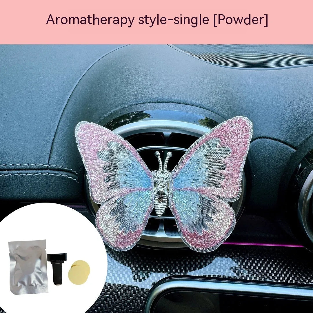 Soft fabric embroidered butterfly car air vent decoration in multiple colour options on a centre console.