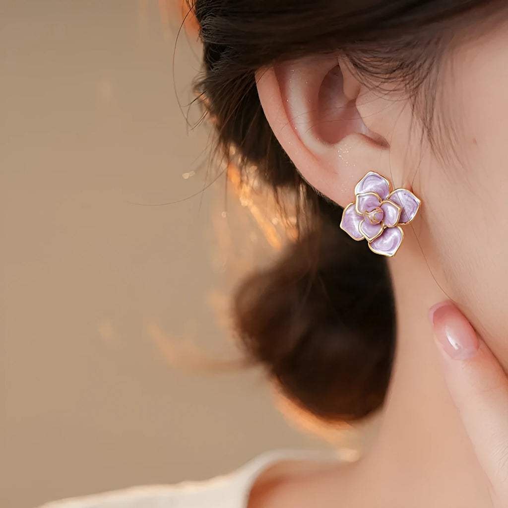A pair of gold-plated purple oil-spot glaze flower stud earrings made from copper, showing detailed floral texture.