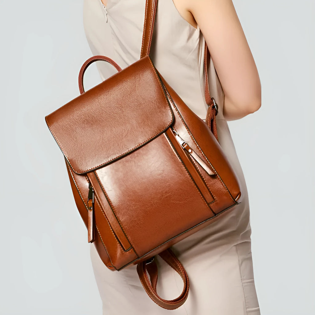 A large black genuine cowhide leather women's backpack with double shoulder straps, shown open to reveal internal zipper and document pockets.
