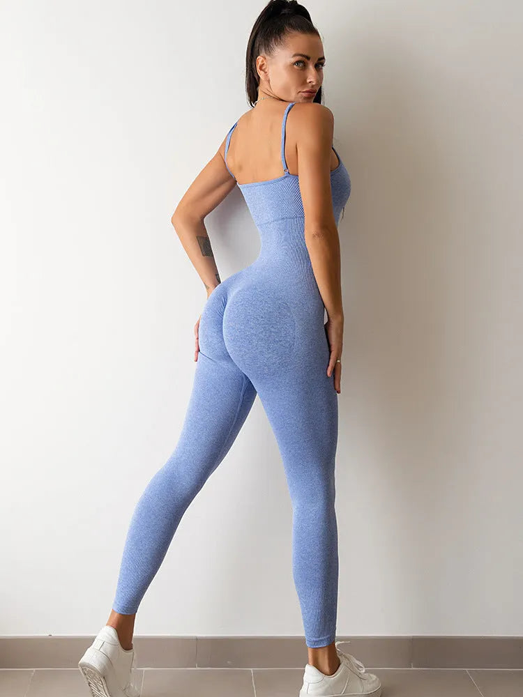 A woman wearing a black sleeveless unitard jumpsuit with spaghetti straps, showing the one-piece design and tummy control panel.