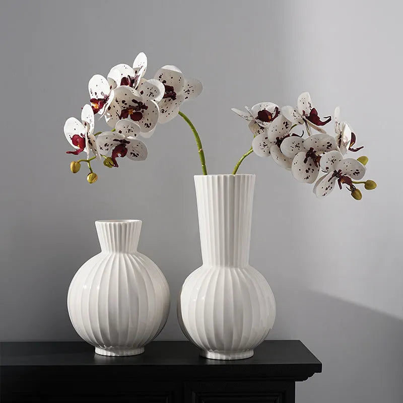 White ceramic ball vase with blue stripes, a silk blue orchid, on a wooden table.