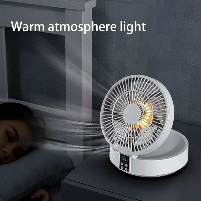 White portable folding electric fan with remote control and warm night light on a desk.
