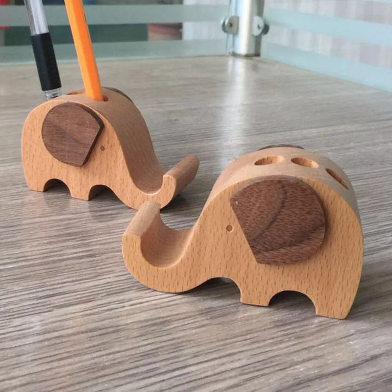 Solid beech wood phone stand with a decorative resin puppy figurine, holding a mobile phone at an angle with a charging cable threaded through the back.