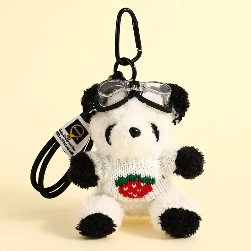 Cute plush strawberry bear doll keychain pendant on a soft surface, showing the cartoon bear with strawberry sweater design