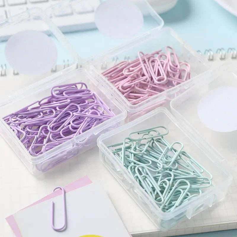 Macaron-color paper clips in pastel shades including pink, green, and purple on a white desk
