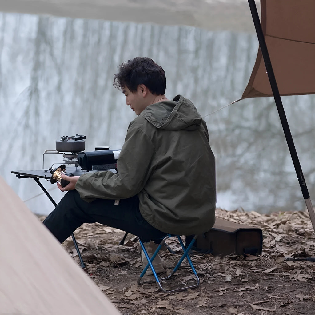 Black ethnic style aluminium alloy folding camping stool shown in use outdoors.