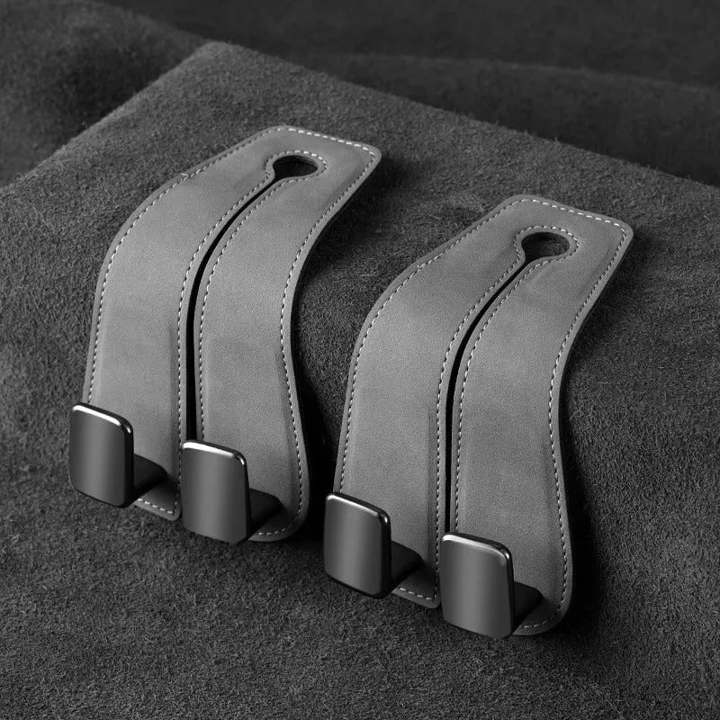 Black car seat hook with suede padding and flip-back design mounted on a grey car seat