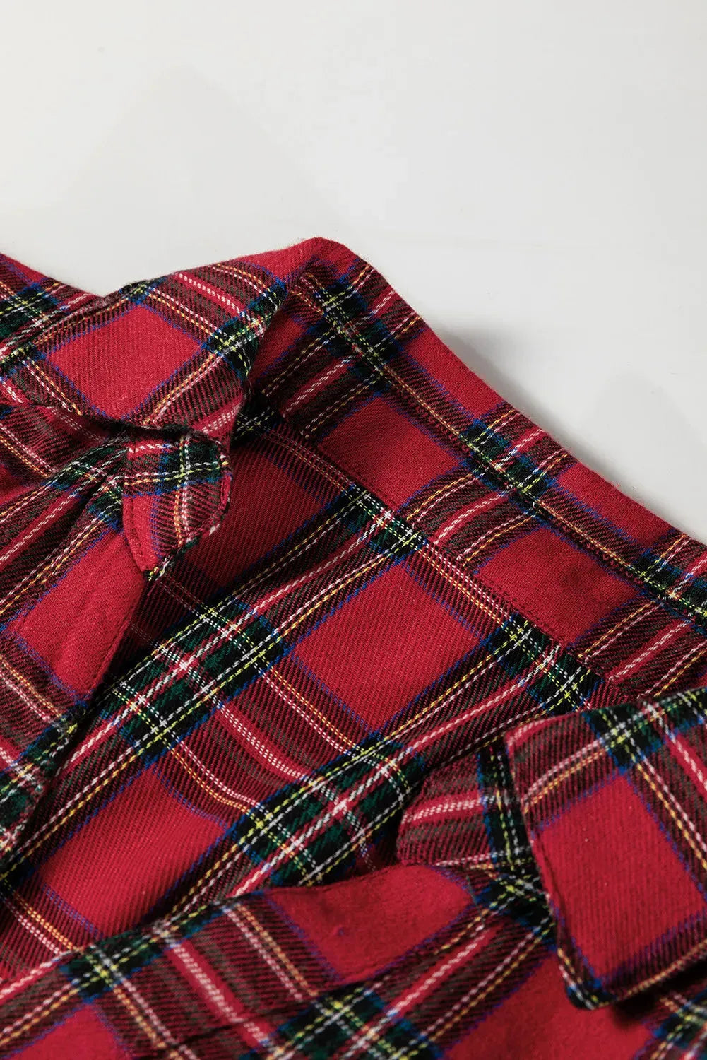 Red plaid mini dress with shirt collar, half-button front, long sleeves, and ruffle hem detailing
