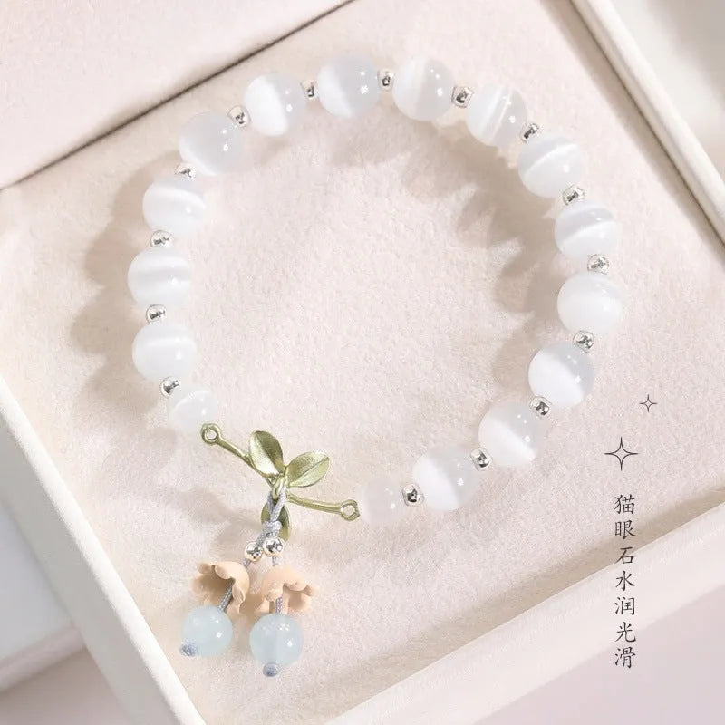 Close-up of a women's opal cat's eye stone beaded bracelet with diamond-shaped beads on a wrist.