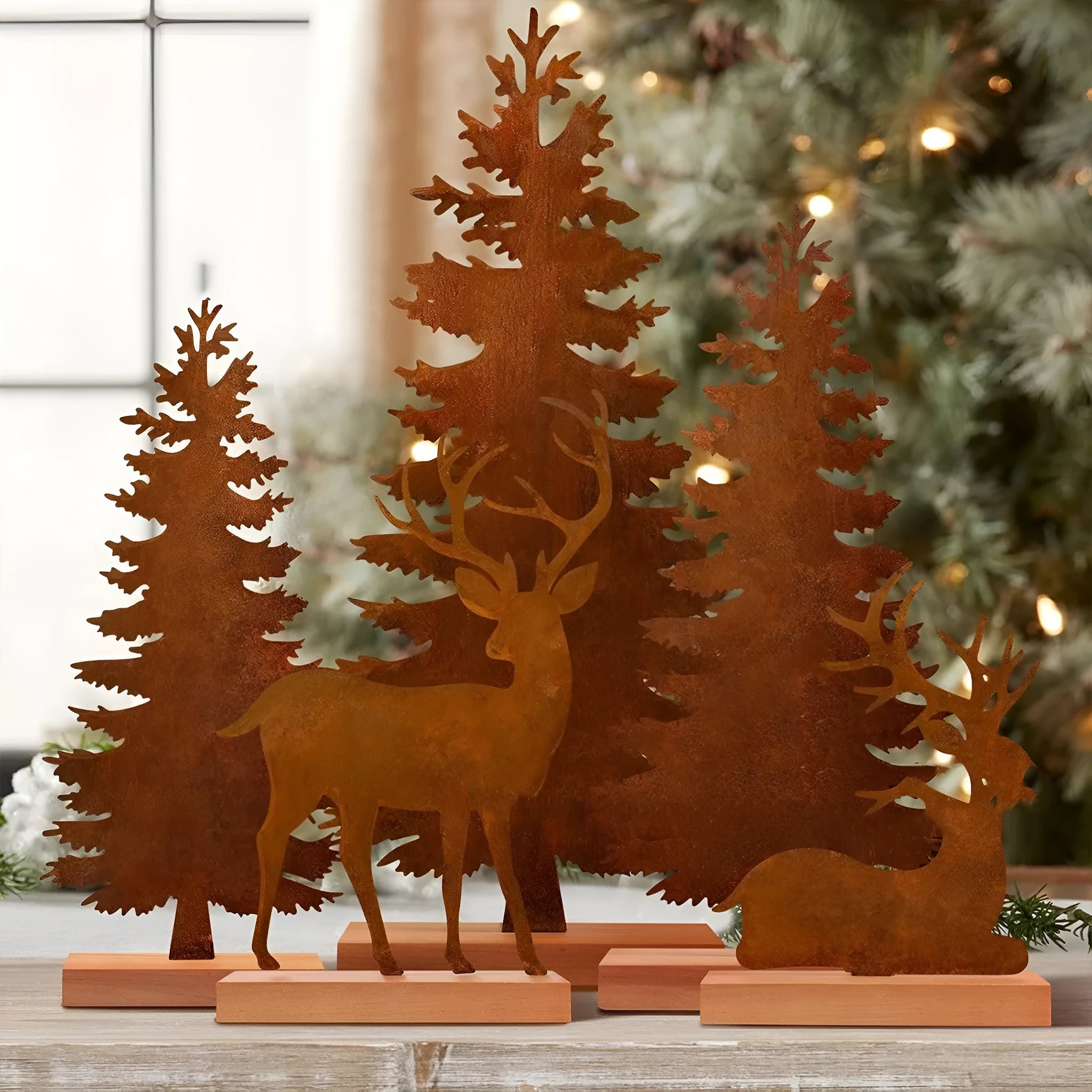 Set of three rustic iron metal Christmas tree and elk silhouette ornaments on a wooden surface.
