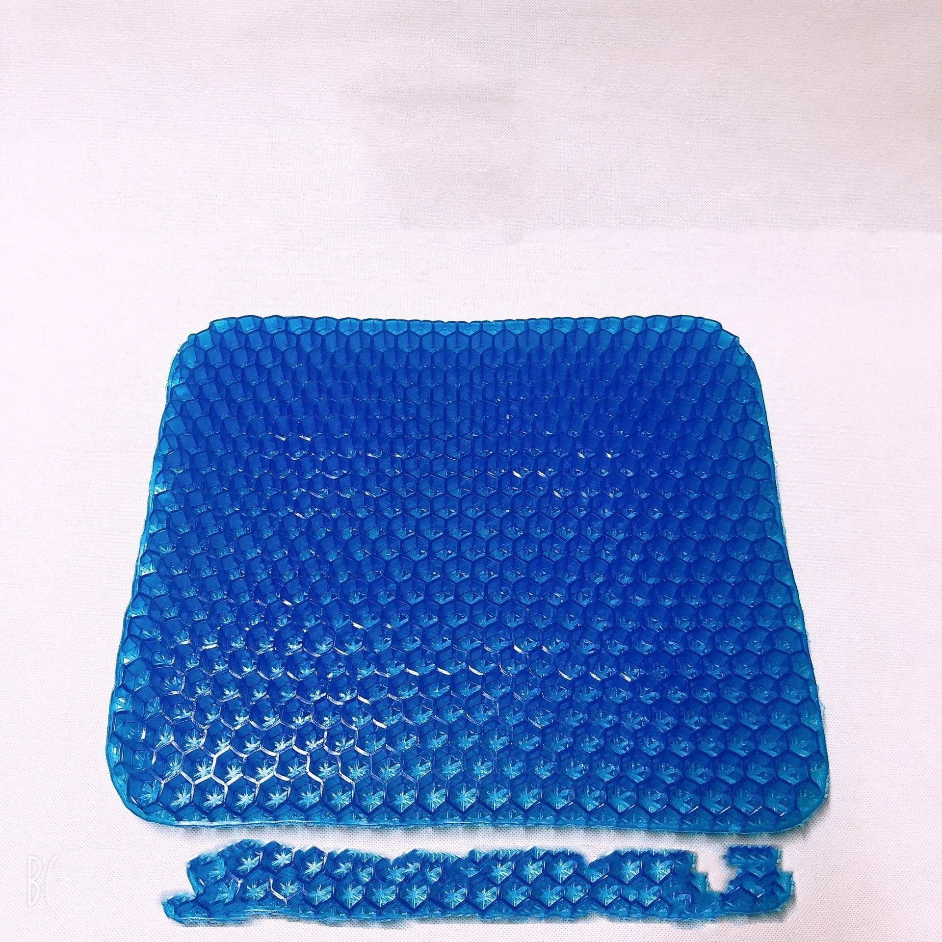 Solid colour gel seat cushion with a honeycomb texture, showing its thickness and removable zippered cover.