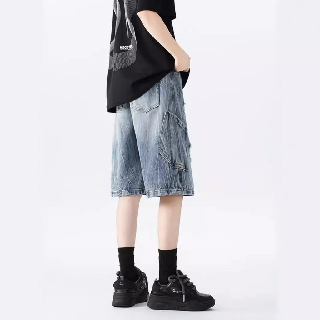 Men's washed denim shorts with ripped detailing in black or blue, showing loose retro style and fifth-pants length