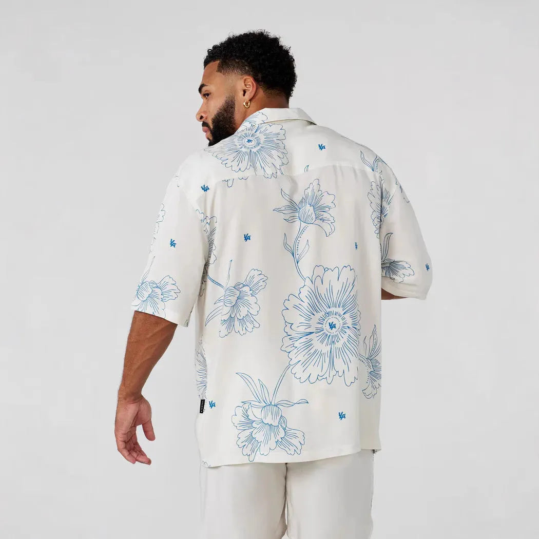 Man wearing a loose, short-sleeved printed floral top in a light colour.