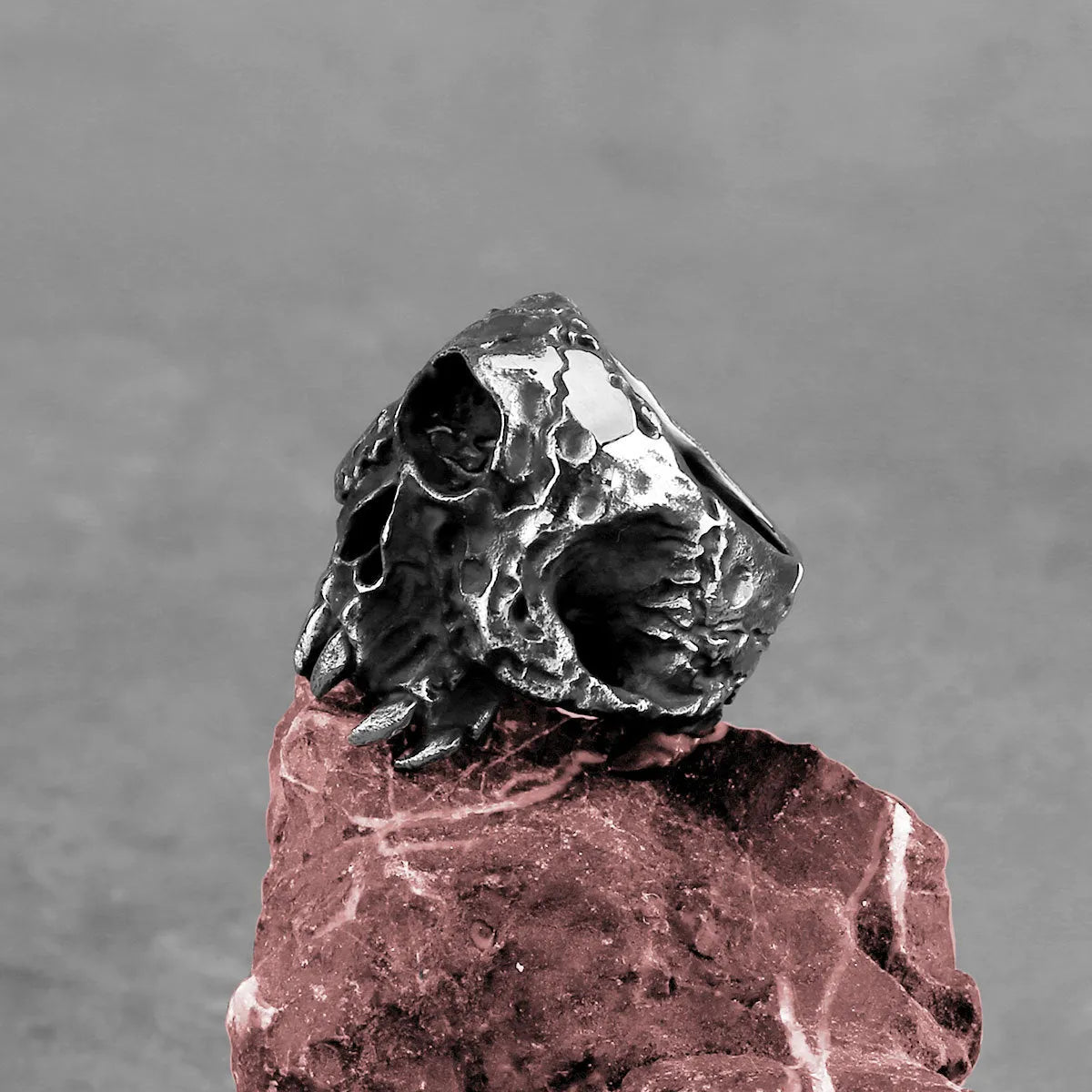 A close-up of a silver-toned alloy ring featuring a detailed one-eyed skull design.