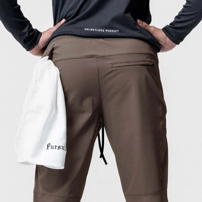 Men's loose grey fitness pants with ankle-tied cuffs laid flat, showing quick-dry polyester fabric.
