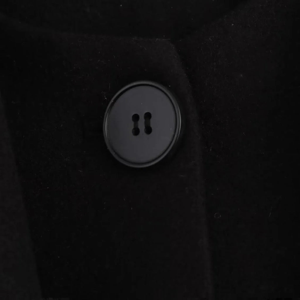 Women's long black coat with artificial fur collar, showing extended length and pocket detail.