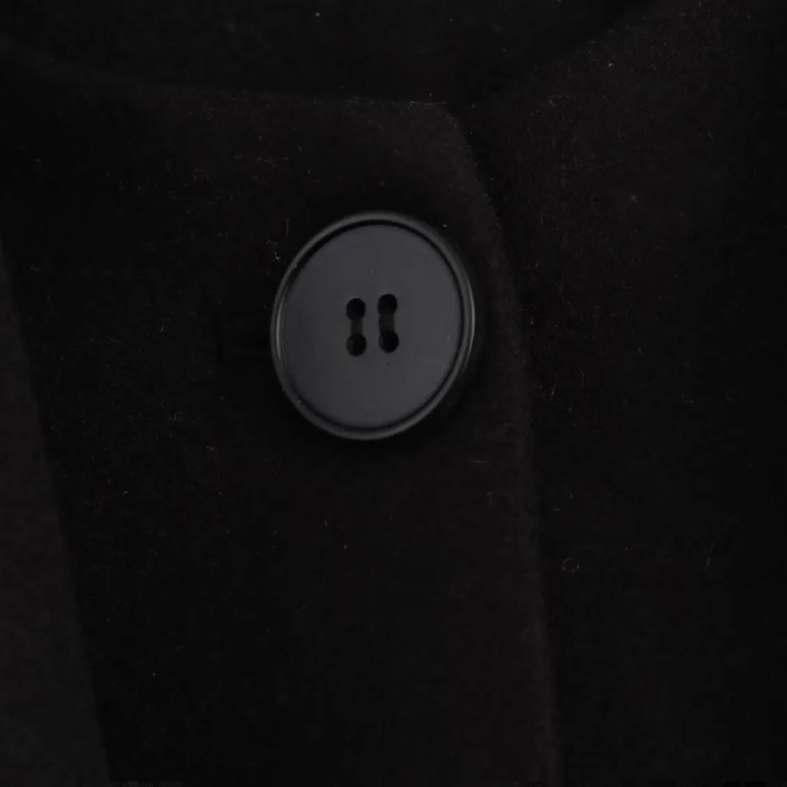 Women's long black coat with artificial fur collar, showing extended length and pocket detail.